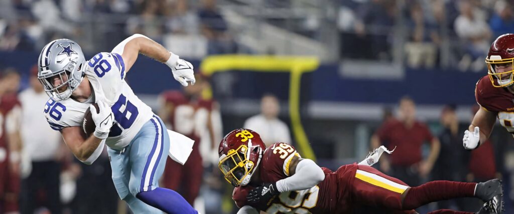 Dalton Schultz Dallas Cowboys evades tackle intense NFL game vibrant stadium athletic action wallpaper