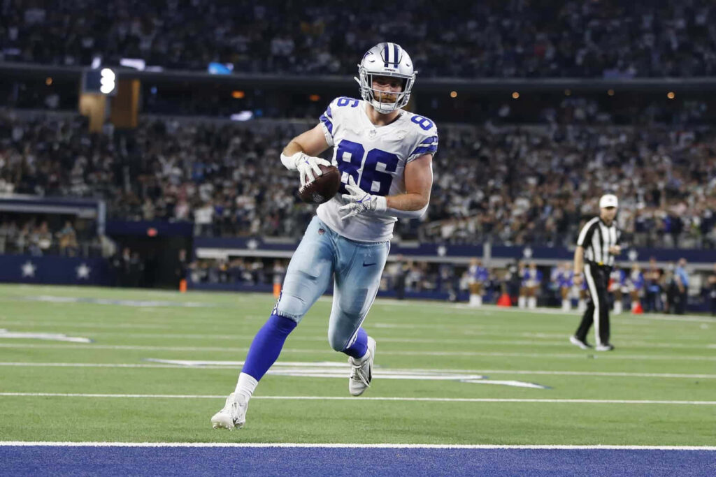 Dalton Schultz Dallas Cowboys running fast evading defenders vibrant stadium lights packed crowd Wallpaper