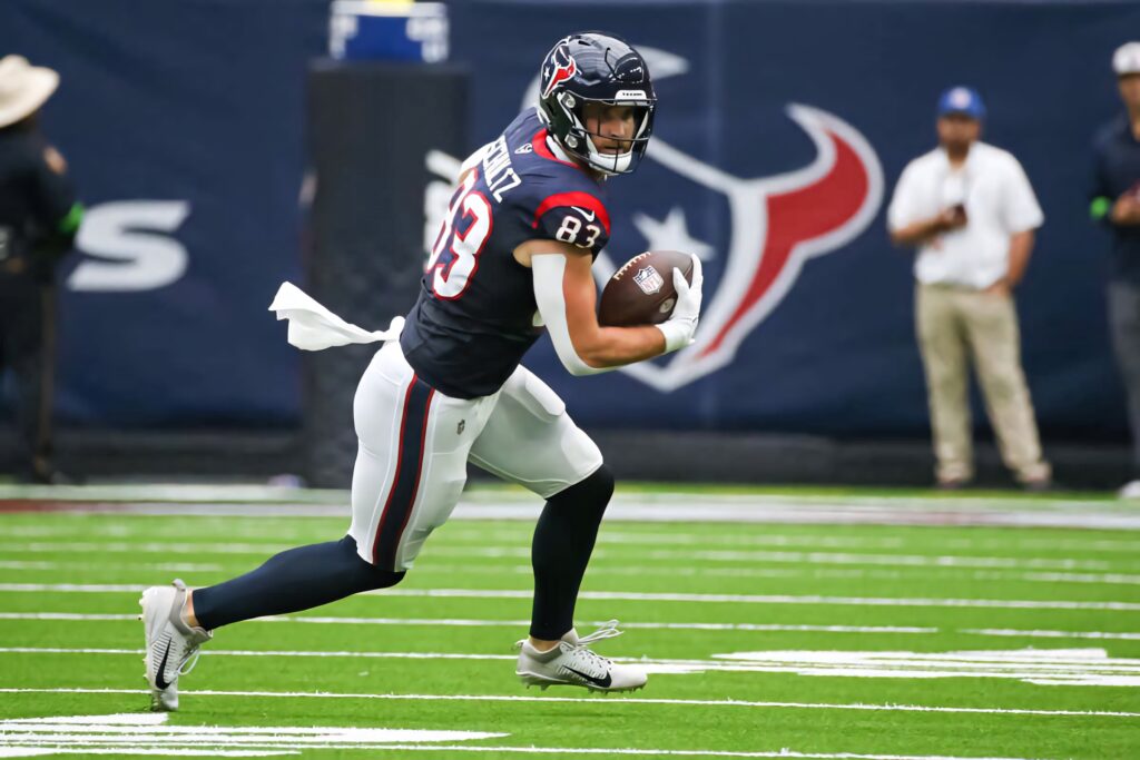 Dalton Schultz Houston Texans number 83 running football on vibrant green field dynamic wallpaper