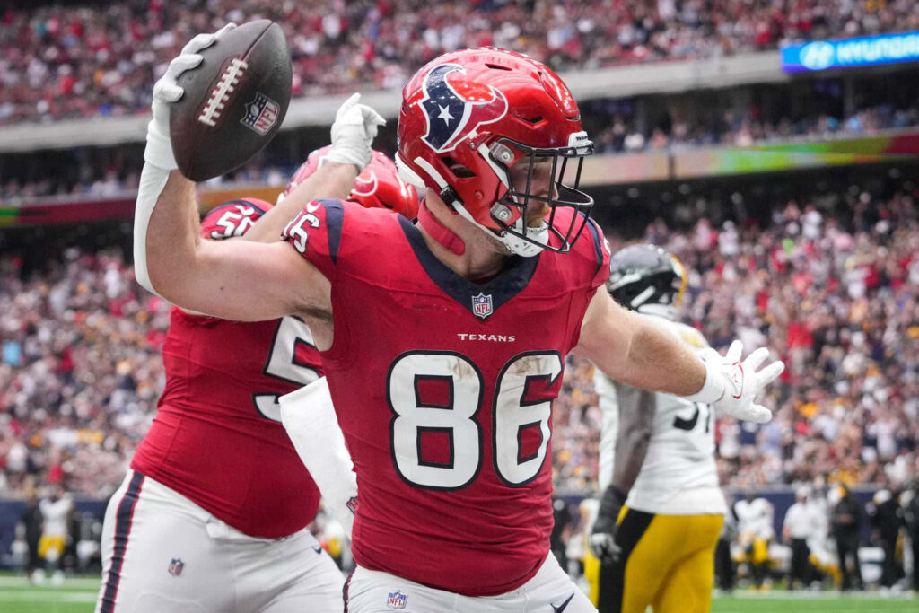 Dalton Schultz Houston Texans red jersey catches football celebrating NFL game vibrant stadium crowd Wallpaper