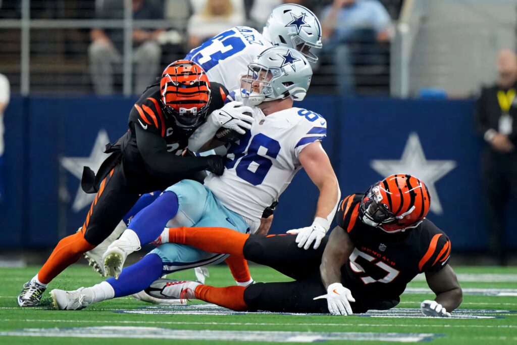 Dalton Schultz tackled by two Cincinnati Bengals defenders in intense NFL football game action Wallpaper