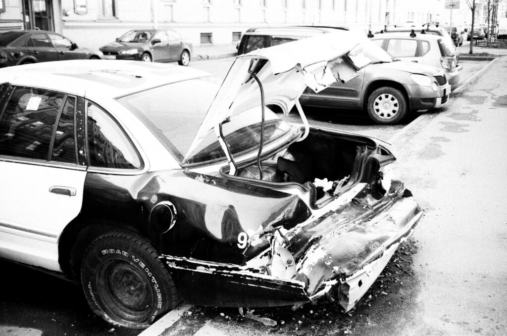 Damaged Car with Dented Trunk from Collision on City Street Wallpaper
