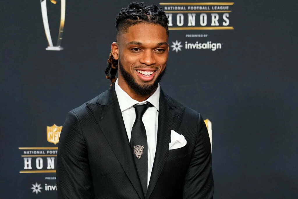 Damar Hamlin in black suit at NFL Honors event with logos backdrop showcasing glamour and prestige Wallpaper