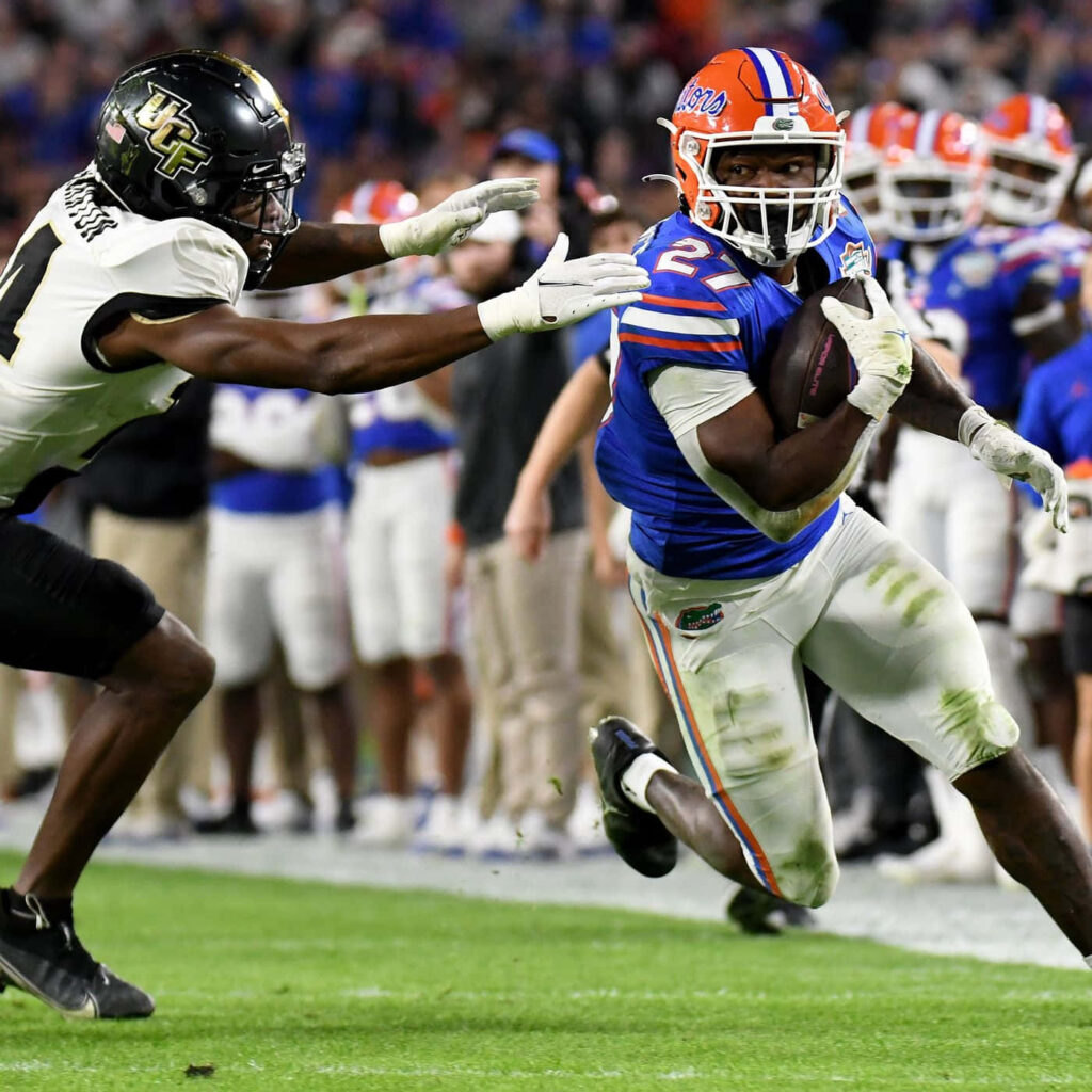 Dameon Pierce in Florida Gators uniform dodges UCF defender in intense college football action Wallpaper