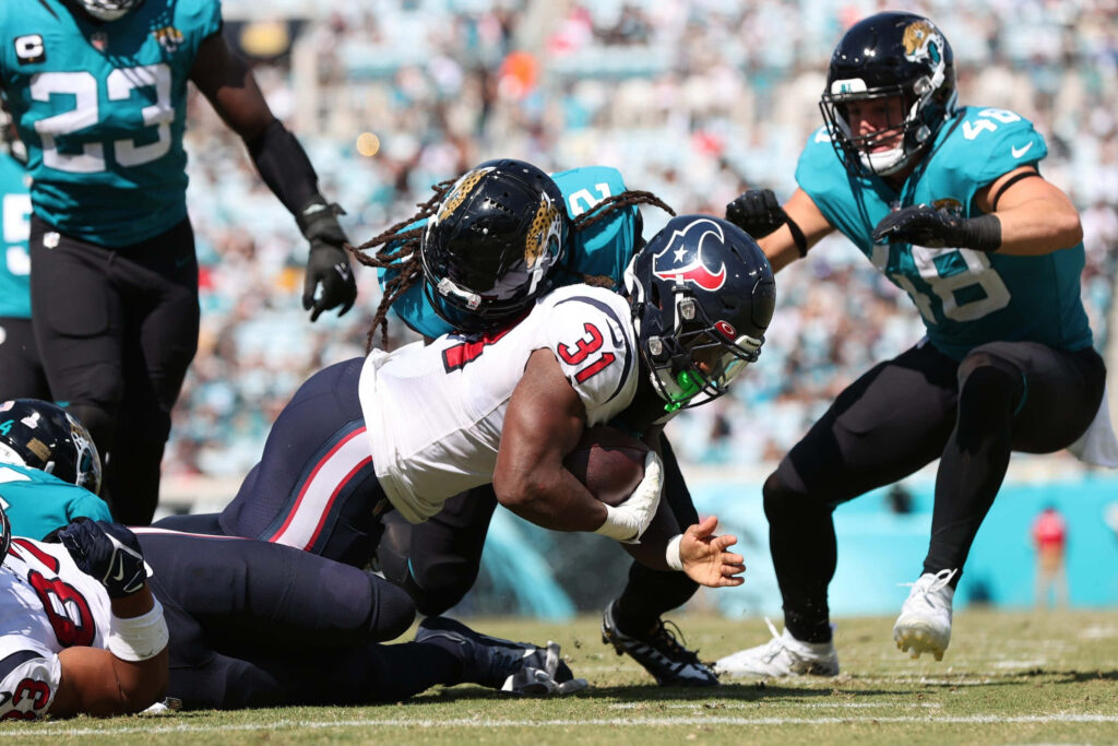 Dameon Pierce charges in football action breaking tackles wearing teal and white jerseys on field Wallpaper