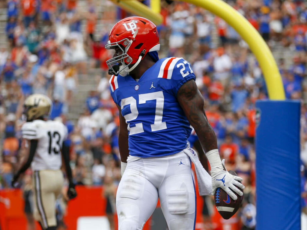 Dameon Pierce running with football in blue and orange number 27 uniform near end zone action Wallpaper