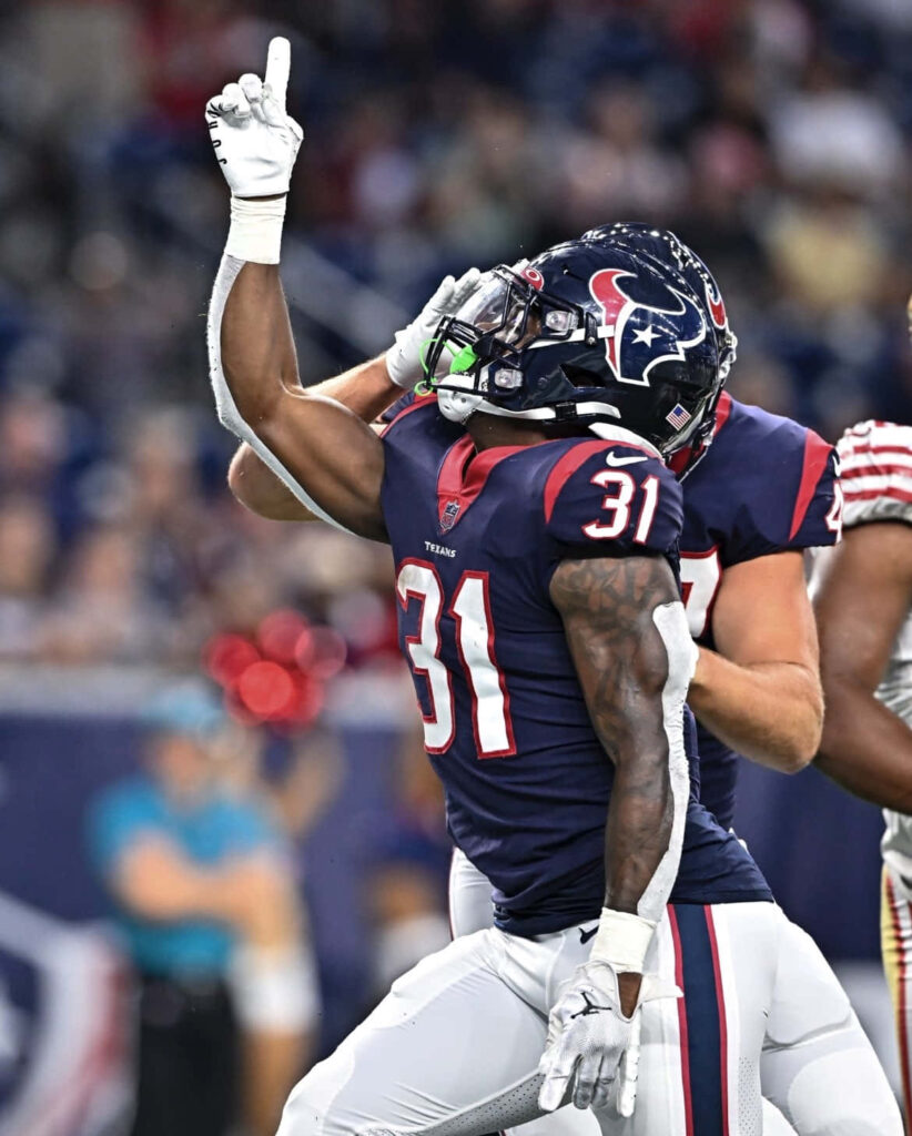 Dameon Pierce Houston Texans celebrates victory raising hand in navy red uniform football field Wallpaper