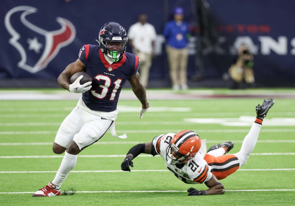 Dameon Pierce Houston Texans running back evades tackle on green turf vs Cleveland Browns intense game Wallpaper