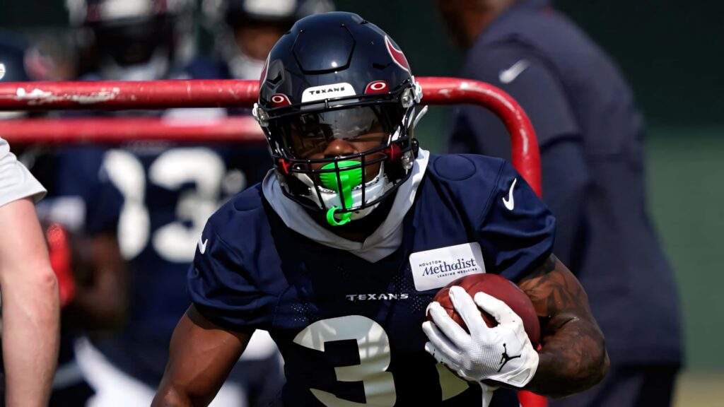 Dameon Pierce Houston Texans in navy gear gripping football showcasing speed and determination Wallpaper