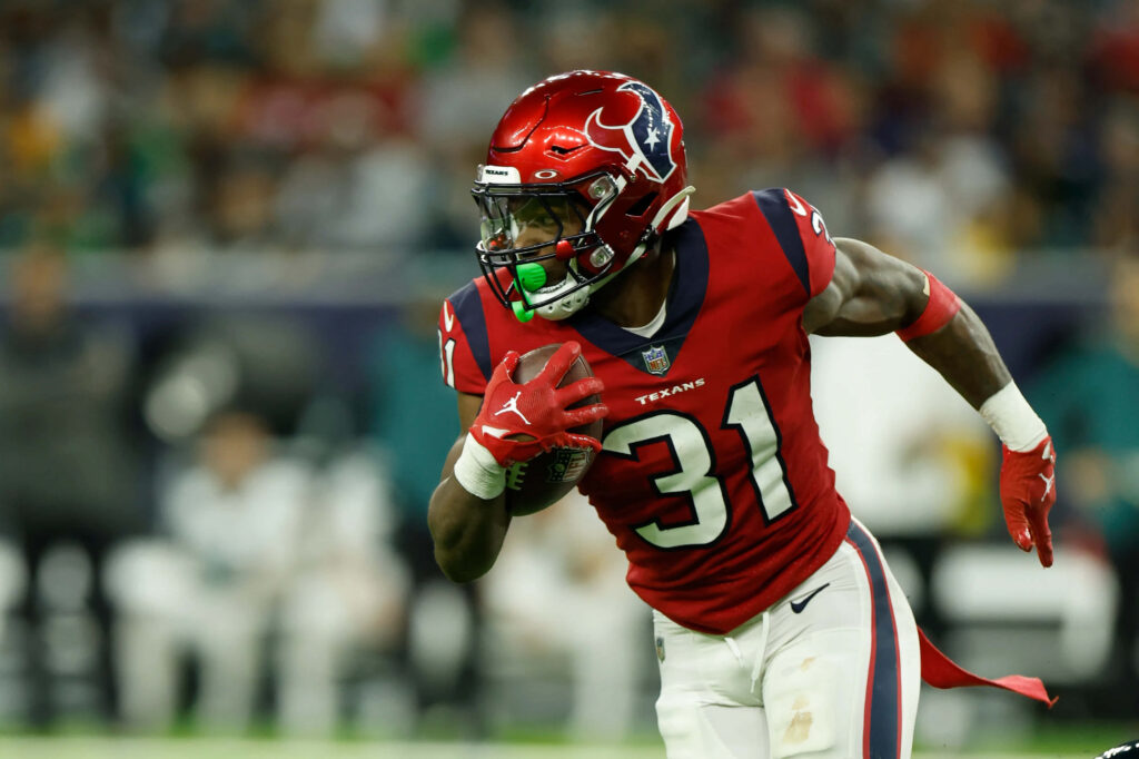 Dameon Pierce Houston Texans running back in red uniform charges forward in action stadium background Wallpaper