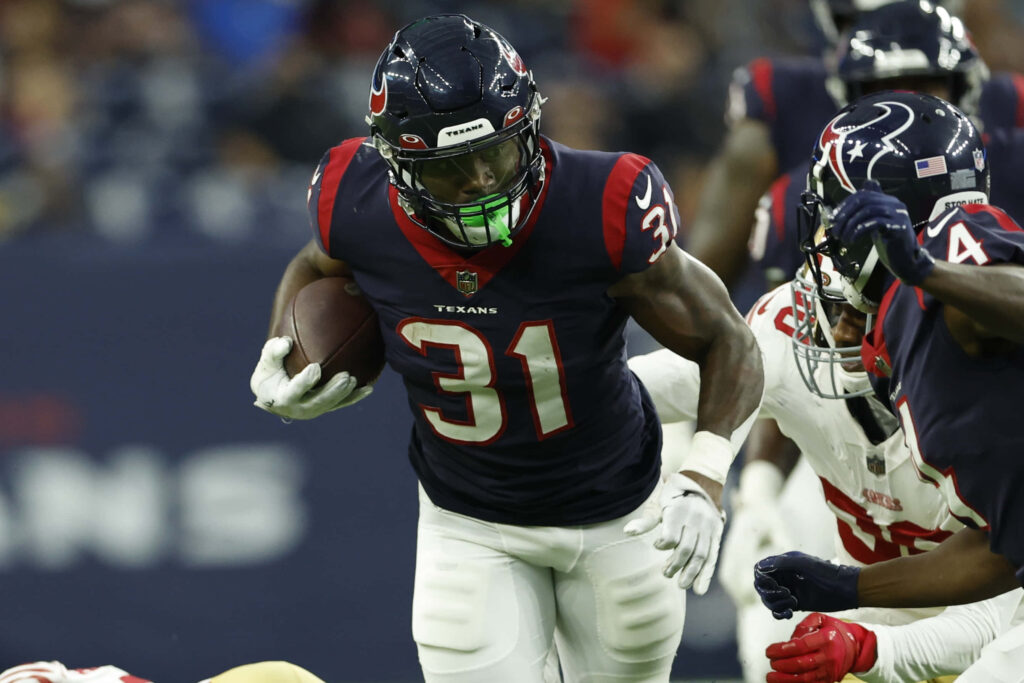 Dameon Pierce Houston Texans running back charges defenders mid-stride in vibrant game action Wallpaper
