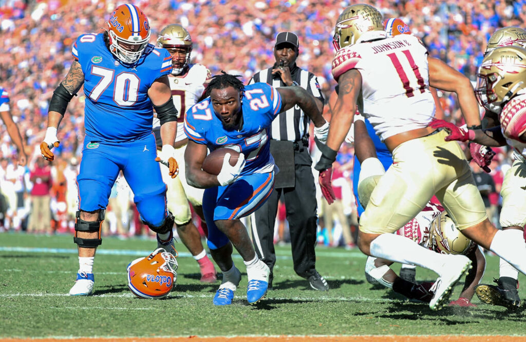 Dameon Pierce bursts through defenders wearing Florida Gators blue and orange uniforms in action Wallpaper