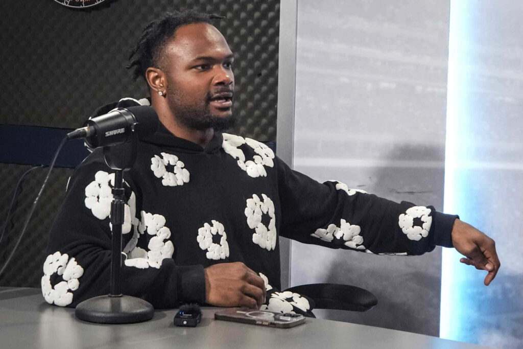 Dameon Pierce in black cloud sweatshirt in modern podcast studio with professional audio gear Wallpaper
