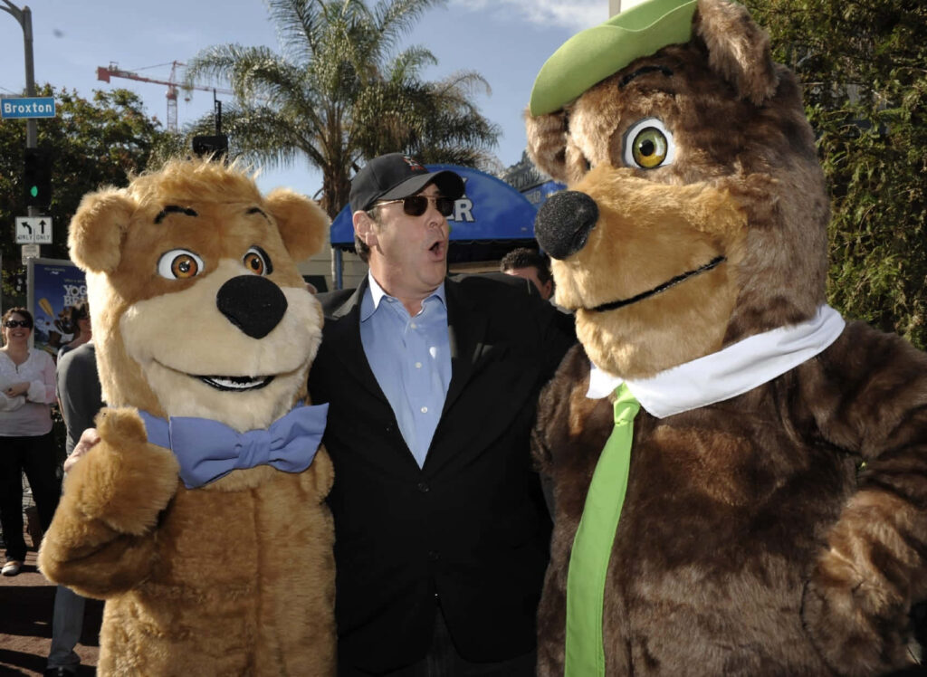 Dan Aykroyd with life-sized Boo-Boo and Yogi Bear under palm trees sunny sky family fun wallpaper