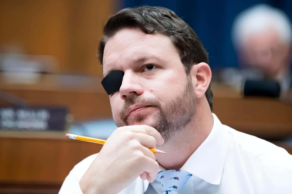 Portrait of Dan Crenshaw with eye patch and beard in formal attire against blurred background Wallpaper
