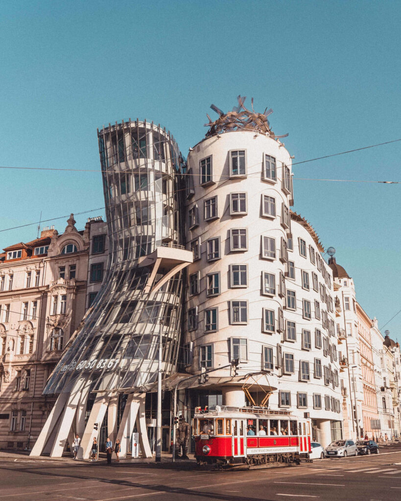 Dancing House Prague with curved glass façades and red tram under clear blue sky urban wallpaper