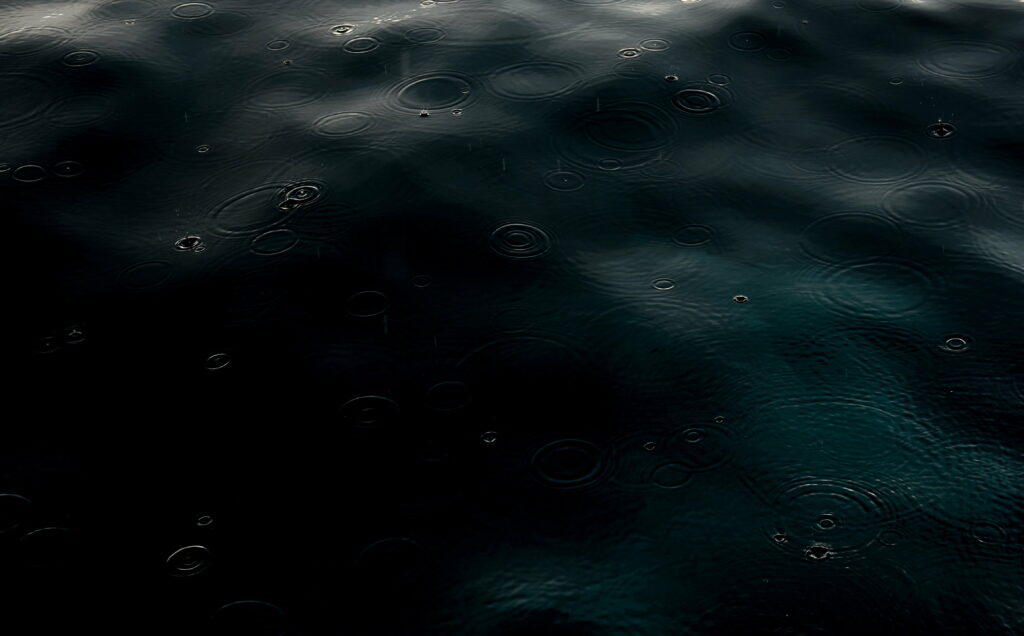 The Ethereal Dance of Rain: Captivating Waves and Glistening Droplets in a Dark and HD Wallpaper Background Photo