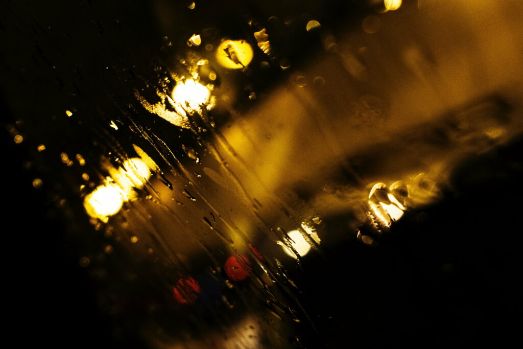 Glistening Raindrops on a Blurred Glass Surface: Mesmerizing Macro Shot Capturing the Play of Lights - Stunning HD Wallpaper Background