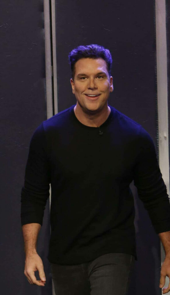 Dane Cook portrait with expressive face in black shirt on dark background modern wallpaper