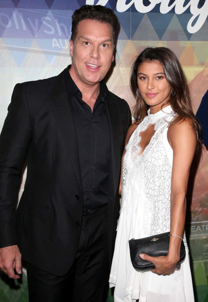 Dane Cook and wife Kelsi Taylor in stylish formal attire with abstract colorful background wallpaper