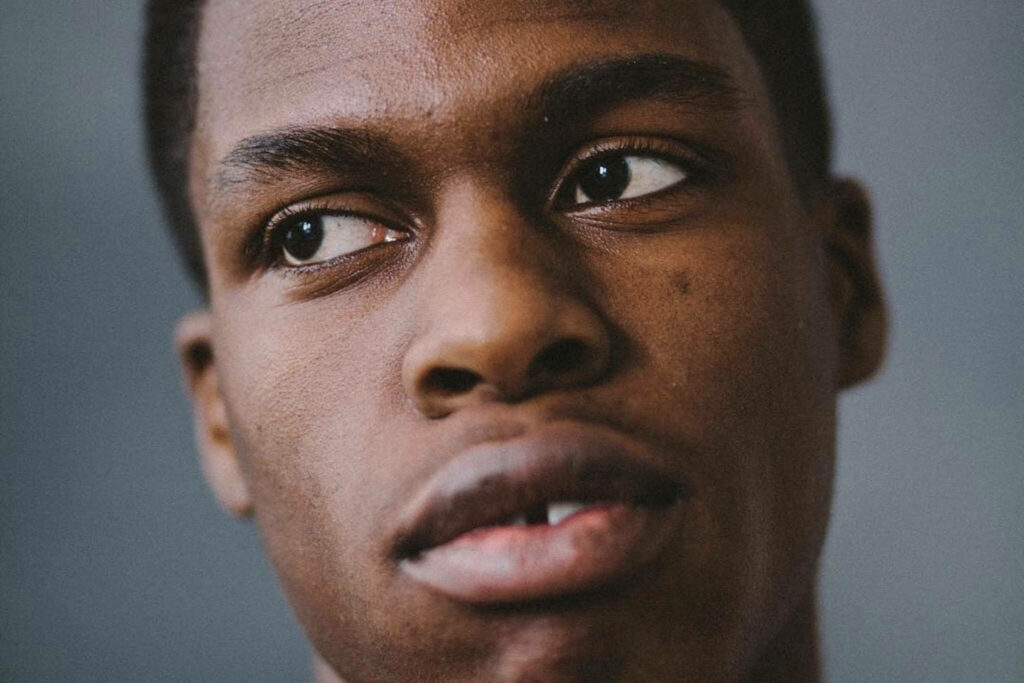Close-up portrait of Daniel Caesar with soft lighting and blurred cool-toned background wallpaper