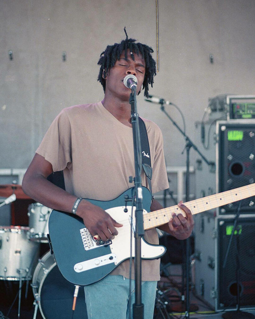 Daniel Caesar live performance wallpaper soulful musician singing playing electric guitar stage
