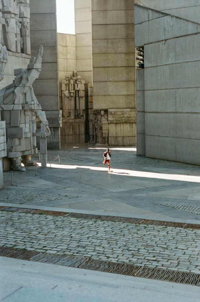 Daniel Caesar walking alone in modern architectural space with towering concrete and soft lighting Wallpaper