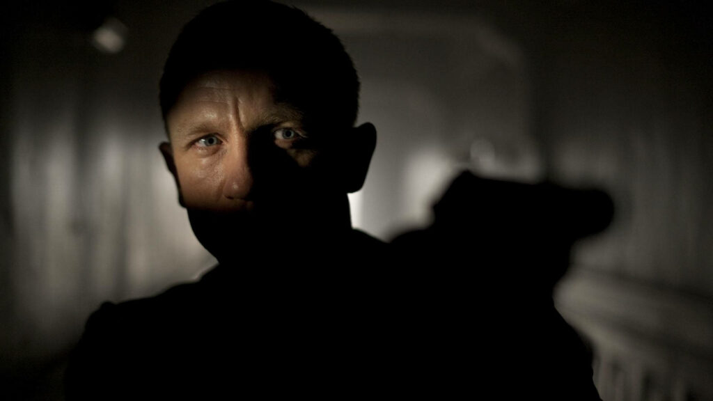 Daniel Craig intense blue eyes in dimly lit corridor creating dramatic suspenseful movie scene wallpaper
