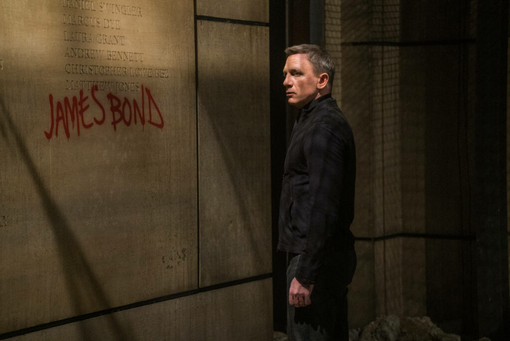 Daniel Craig in tense James Bond scene looking at red graffiti wall with James Bond text wallpaper