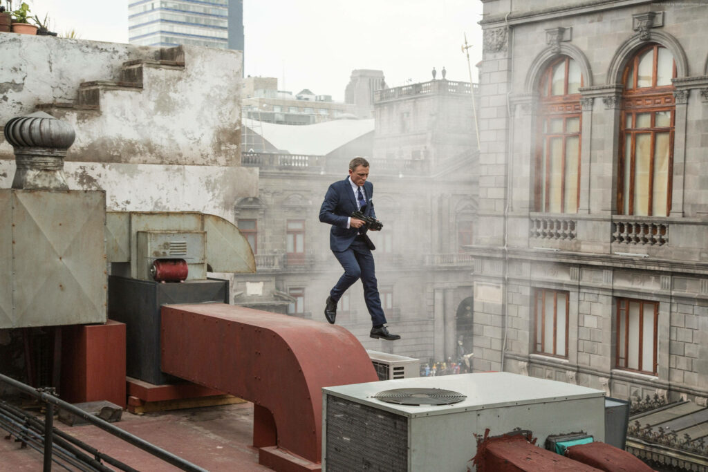 Daniel Craig in sharp suit jumping rooftops intense action urban chase thriller wallpaper background