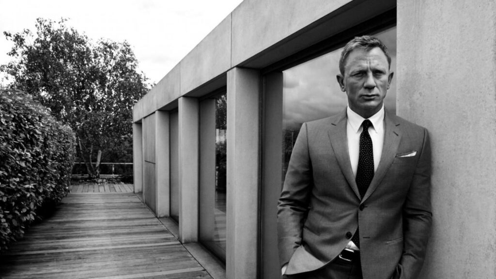 Daniel Craig in sharp suit grayscale wallpaper modern architecture background sophistication intensity
