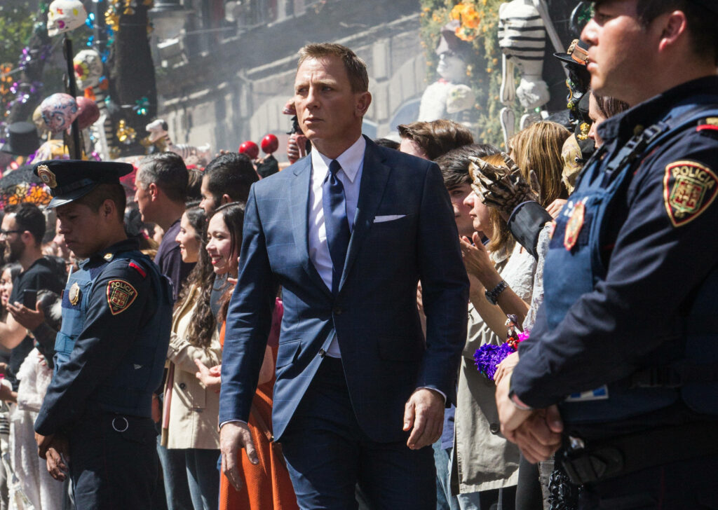 Daniel Craig in sharp suit exuding charisma amid a bustling crowd movie wallpaper background