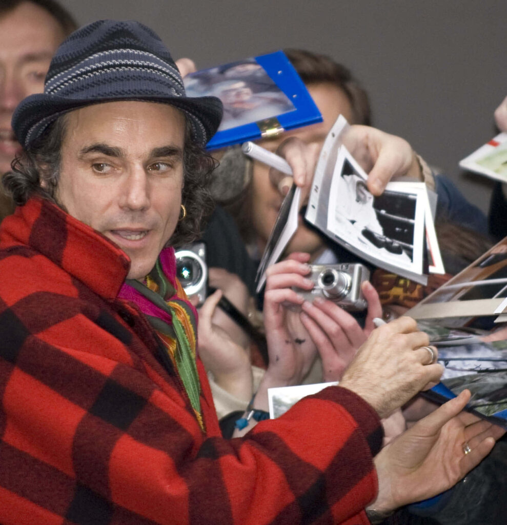 Daniel Day Lewis signing autographs in plaid jacket and fedora at lively public event Wallpaper