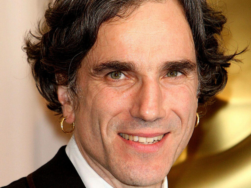 Close-up of Daniel Day-Lewis smiling with golden ear hoops warm lighting and blurred background Wallpaper