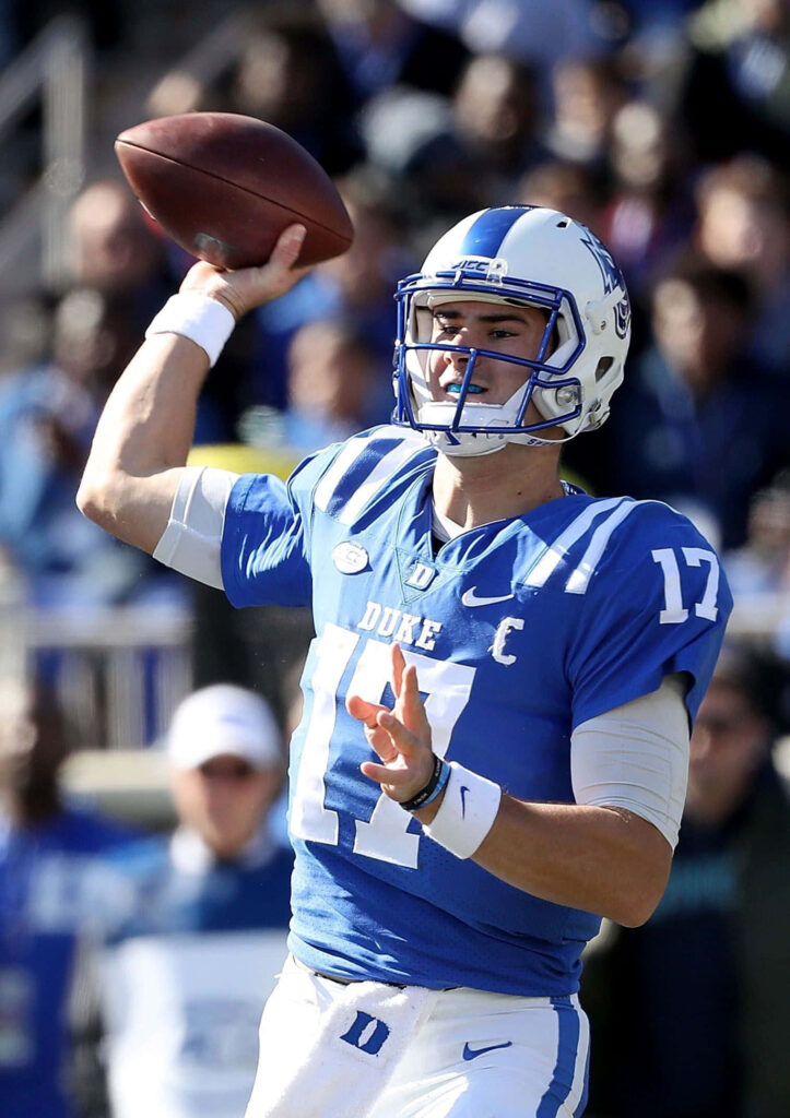 Daniel Jones Duke quarterback mid-throw in vibrant blue white uniform dynamic game action wallpaper