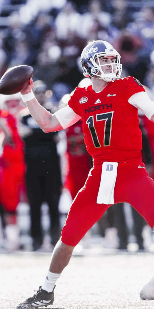 Daniel Jones throwing football in red North team uniform number 17 with Duke helmet in stadium Wallpaper