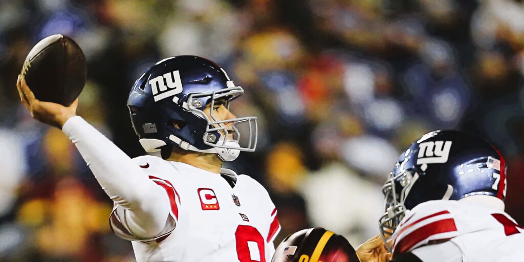 Daniel Jones New York Giants quarterback mid-throw in blue helmet white jersey under stadium lights Wallpaper