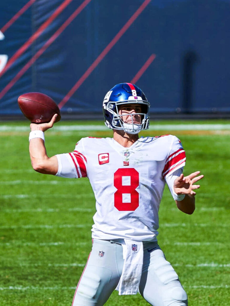 Daniel Jones New York Giants quarterback in action throwing football vibrant stadium background Wallpaper