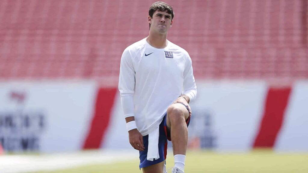 Daniel Jones New York Giants on football field in white shirt blue shorts during practice Wallpaper