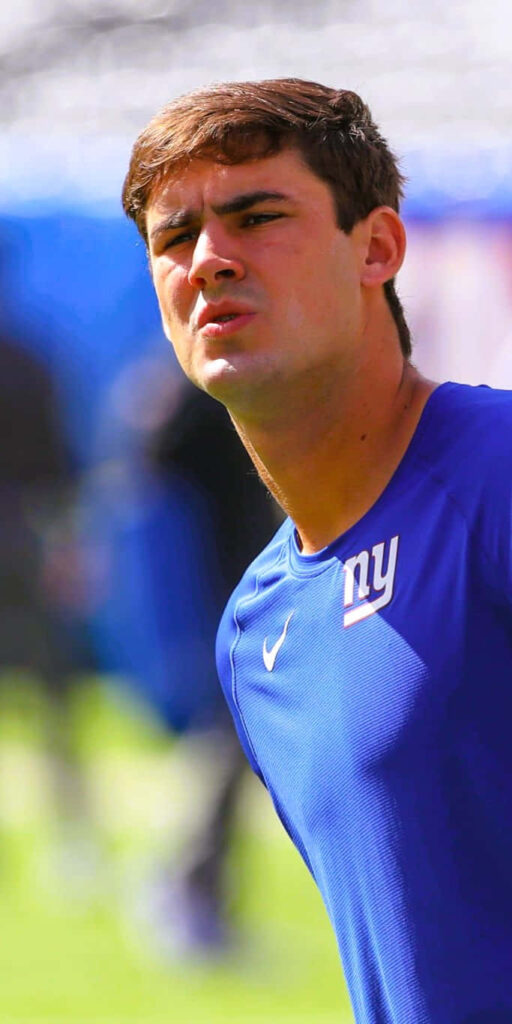 Daniel Jones in blue Giants shirt focused on field vibrant stadium background wallpaper