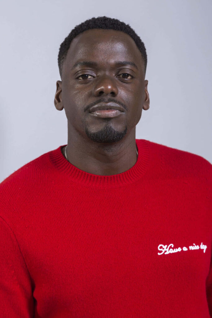 Daniel Kaluuya in red sweater with Have a nice by embroidery on light gray studio background Wallpaper