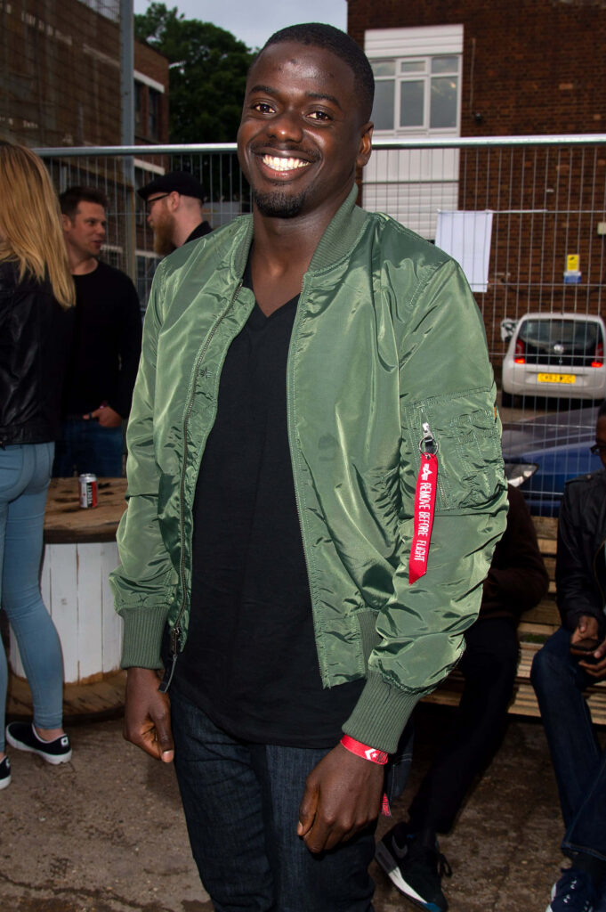 Daniel Kaluuya smiling outdoors in green bomber jacket black shirt at casual urban event wallpaper background