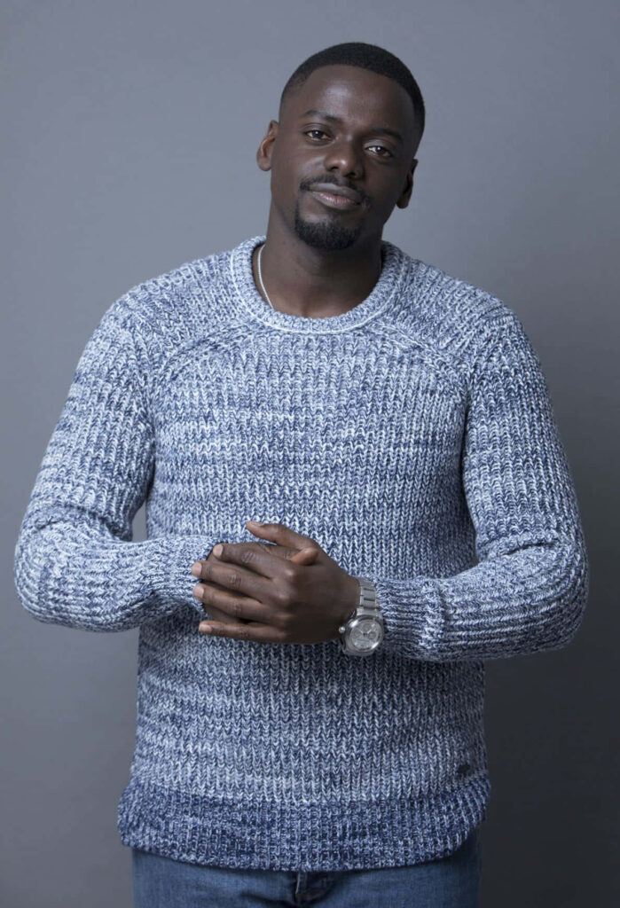 Daniel Kaluuya in blue and white knit sweater with watch confident portrait on gray background Wallpaper