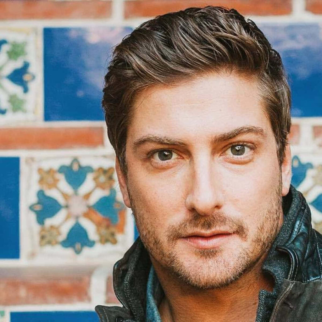 Daniel Lissing portrait with expressive gaze colorful patterned tiles and brickwork background natural light Wallpaper
