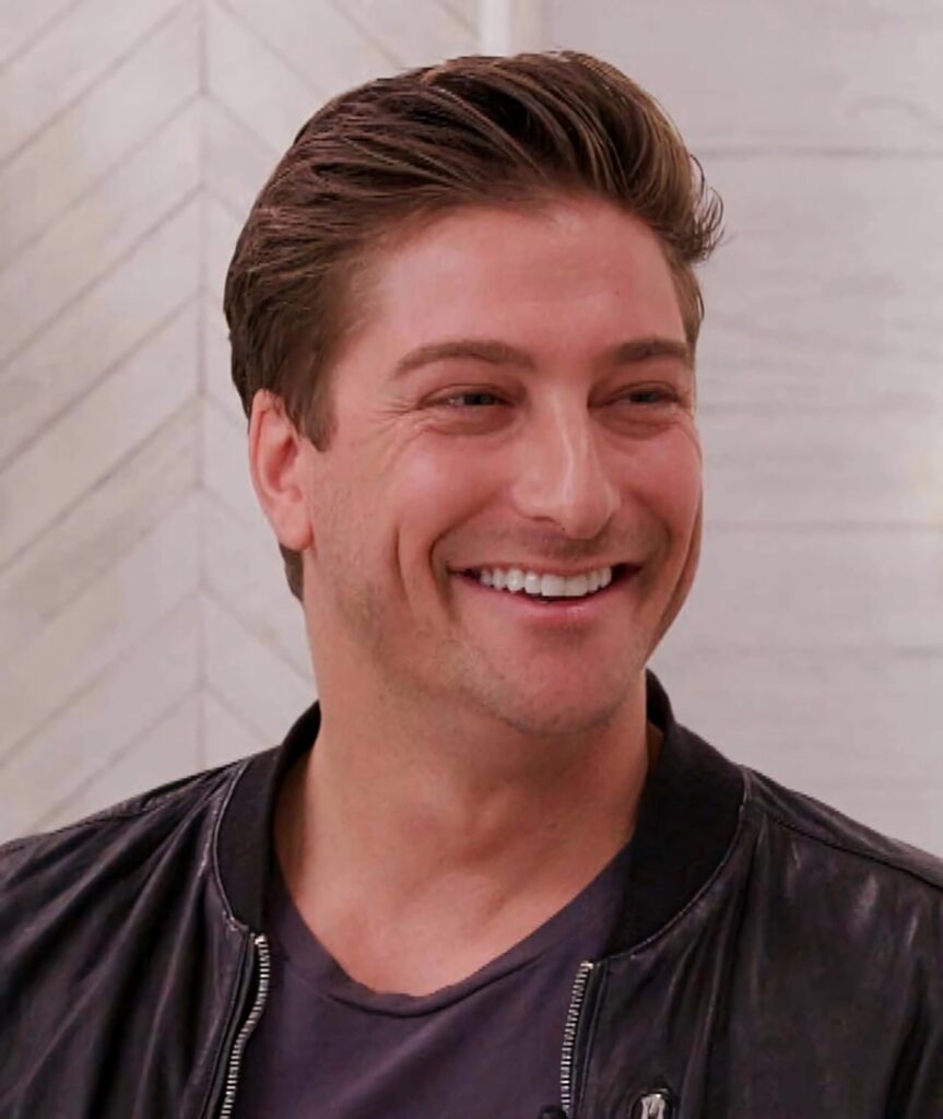 Daniel Lissing smiling in black leather jacket with chevron background soft natural lighting Wallpaper