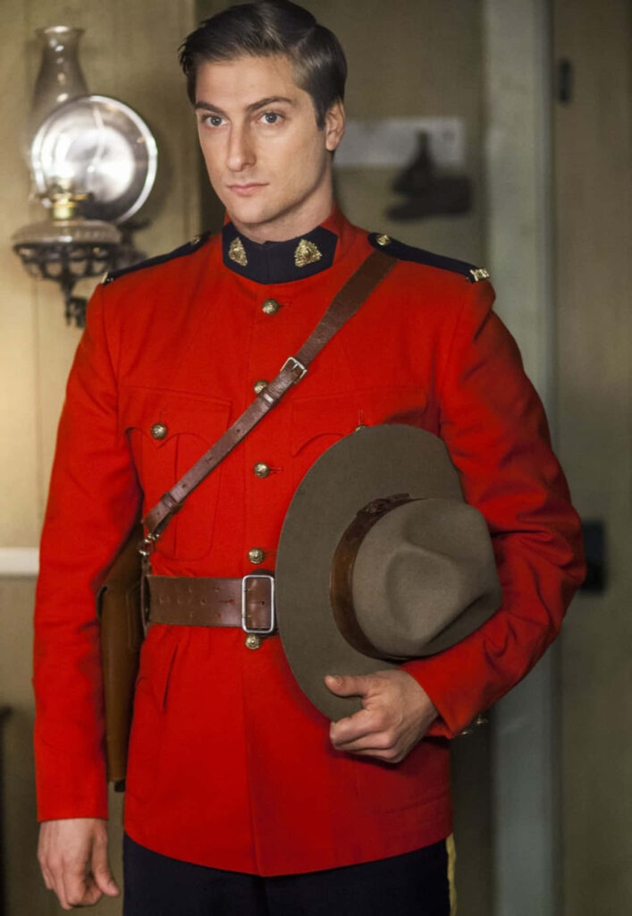 Daniel Lissing in classic red Royal Canadian Mounted Police uniform holding hat indoors vintage look Wallpaper