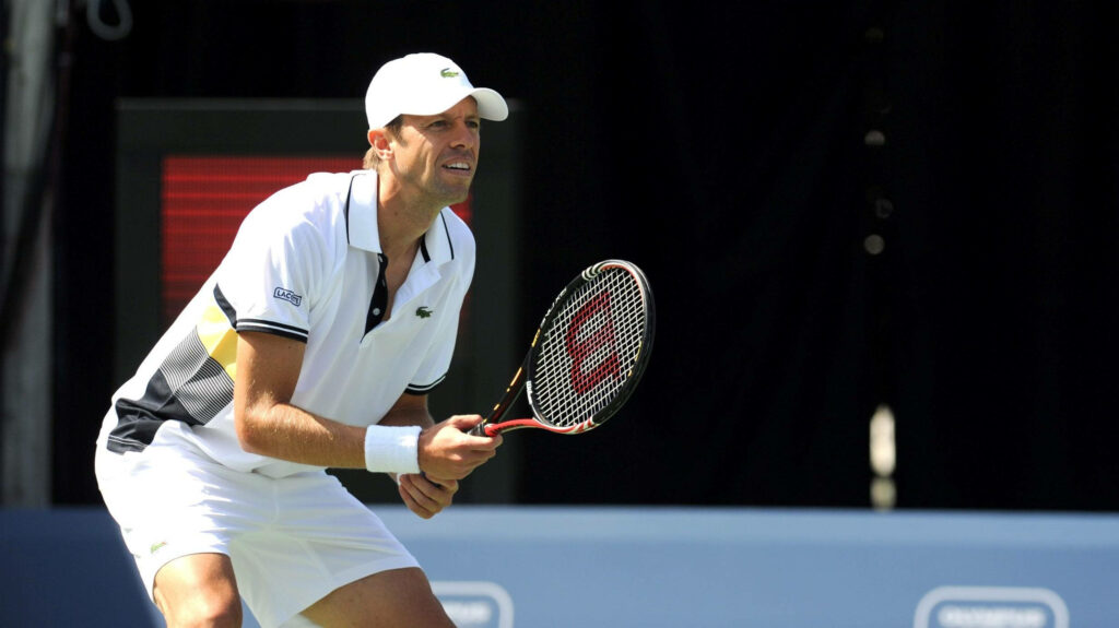 Daniel Nestor focused tennis player in white Lacoste outfit ready to play against dark background Wallpaper