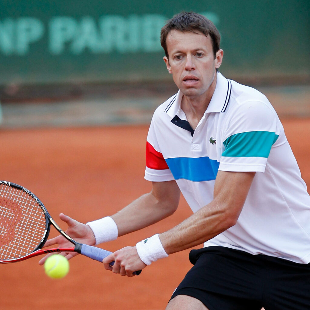 Daniel Nestor focused returning tennis ball on clay court in white striped shirt vibrant sports action Wallpaper