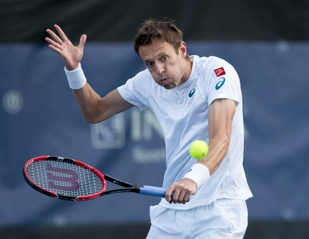 Tennis pro Daniel Nestor in white gear hitting a sharp stroke showing focus and athletic form Wallpaper