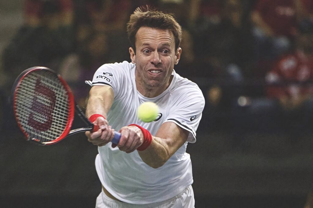 Daniel Nestor tennis player returning shot with intense focus during match action wallpaper background
